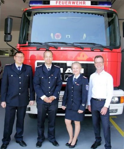 Herr Stamer steht mit Kameradinnen und Kameraden der Freiwilligen Feuerwehr Mönchhagen vor einem Löschfahrzeug.